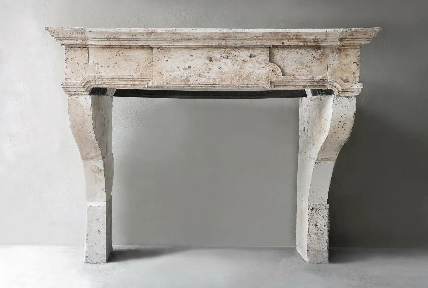 Frontaal zicht op antieke 18e-eeuwse Franse kalkstenen schouw met S-vormige poten en originele patina